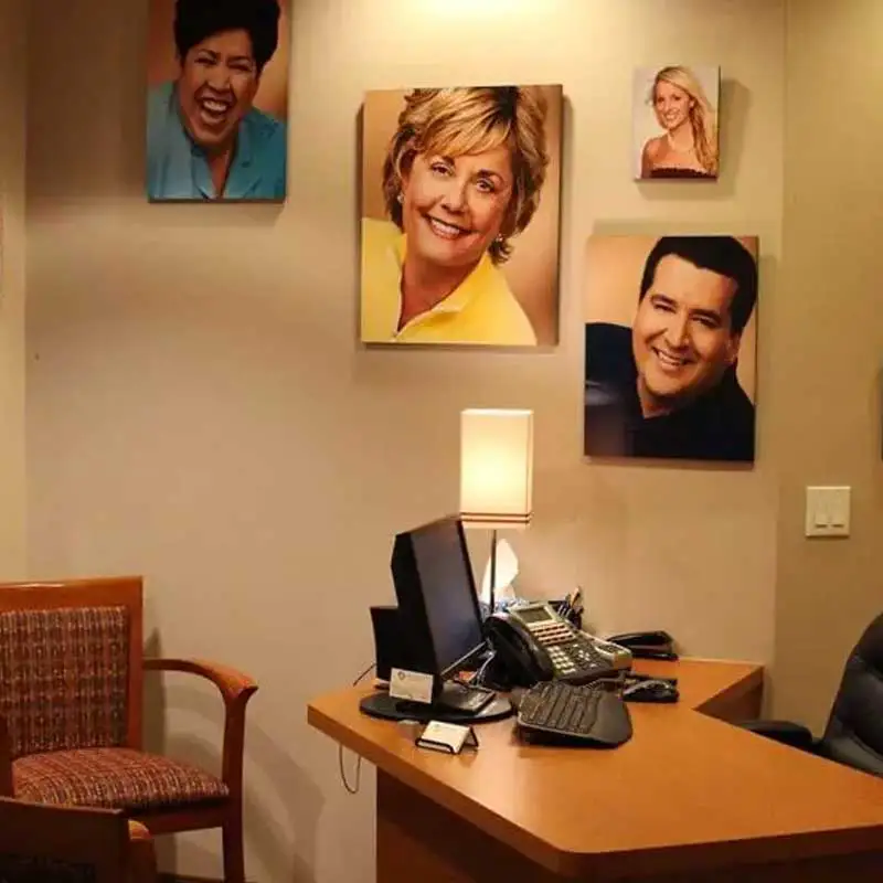 A desk in a room with portraits of happy smiling clients at GOREgeous Smiles 