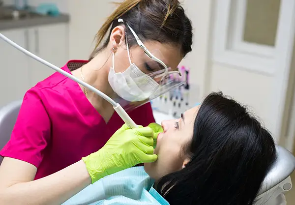 A dental hygienist completing a routine dental cleaning procedure on the teeth of a relaxed female patient at a Scottsdale dental office.